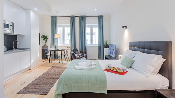 Een moderne hotelkamer met een bed, een eethoek en een kitchenette.