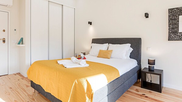 Ein modernes Hotelzimmer mit einem großen Bett, einem Nachttisch und einer Wandleuchte.