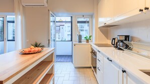 Een moderne keuken met witte kastjes, een houten aanrechtblad en uitzicht naar buiten.
