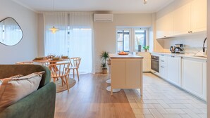 Een moderne keuken met witte kasten, een centraal eiland en een eethoek met een ronde tafel en stoelen.