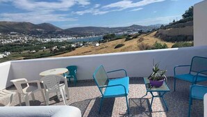 A terrace with blue and white chairs, a small table, and a potted plant. - Penthouse studio overlooking Paroikia Bay! (Paros)