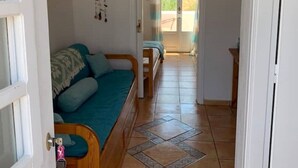 Una stanza con un divano in legno, un tavolino e vista sull'esterno attraverso una porta.