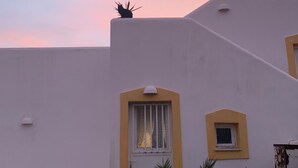 Un edificio con facciata bianca e dettagli gialli, dotato di una piccola finestra e un elemento decorativo sul tetto.