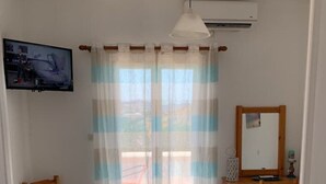Camera da letto con due letti, una televisione, una scrivania e una finestra con tende.