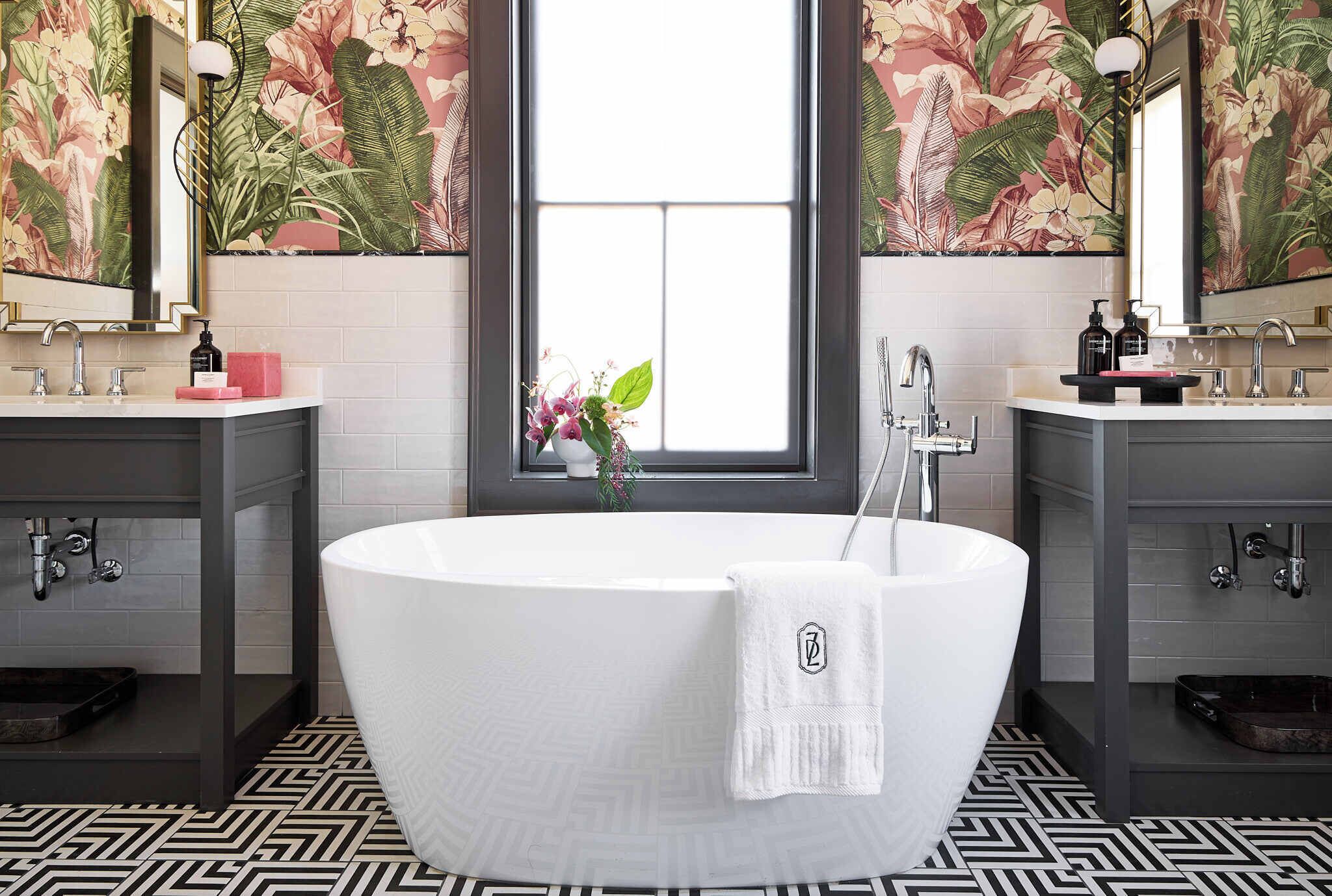 A bathroom with a freestanding bathtub, two vanity sinks, and a window with a view.