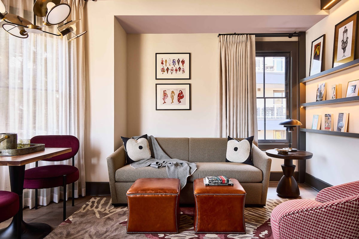 A living room with a sofa, ottomans, a table with chairs, and artwork on the walls.
