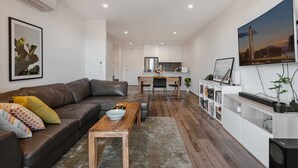 Un salon moderne avec un canapé en cuir, une table basse en bois et une cuisine en arrière-plan.
