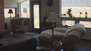 A living room with a large window, a lamp, a chair, and a rug. - Snow Capped MTN View & Starry Nites: 1 hour to Great Sand Dunes & Monarch Skiing (Crestone)