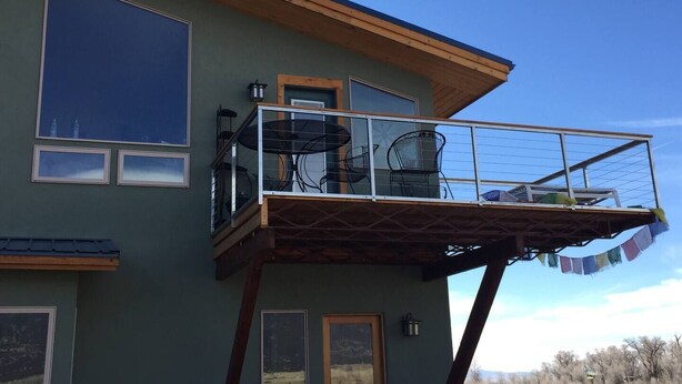 A two-story building with a balcony featuring outdoor furniture. - Snow Capped MTN View & Starry Nites: 1 hour to Great Sand Dunes & Monarch Skiing (Crestone)