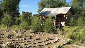 A rustic cabin with a stone exterior, surrounded by a maze-like garden of rocks and sparse vegetation. - Snow Capped MTN View & Starry Nites: 1 hour to Great Sand Dunes & Monarch Skiing (Crestone)