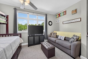 A bedroom with a bed, a TV, a sofa, and a window with a view of trees. - #2203 Pointe - Studio Suite at Mariners SML (Huddleston)