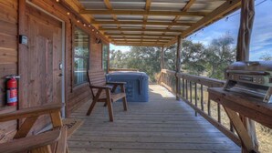 A wooden deck with a covered area, a barbecue grill, and a hot tub.