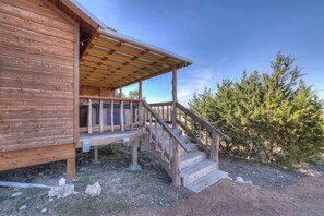 A wooden cabin with a wooden deck and stairs leading to a covered porch.