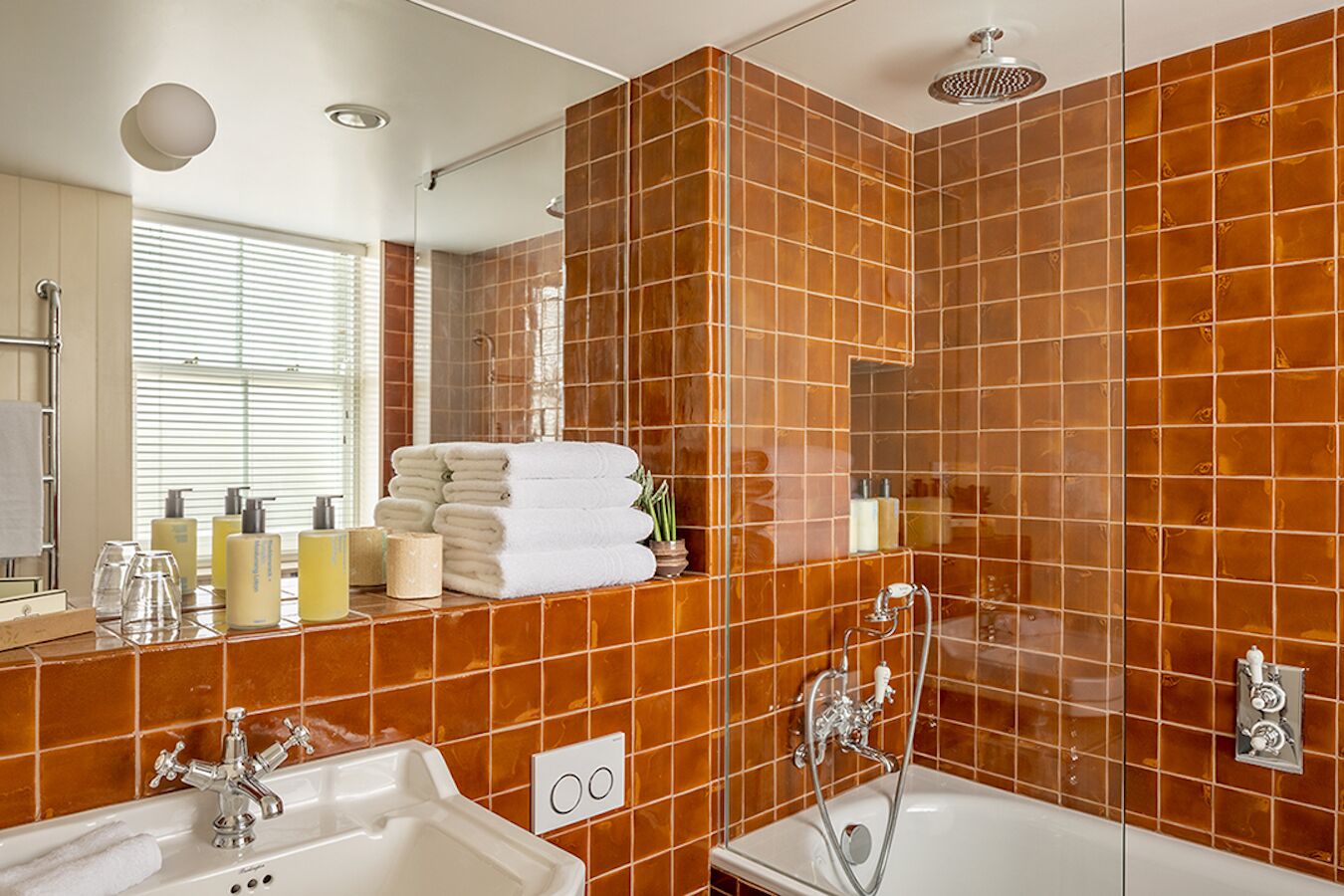 Ein modernes Badezimmer mit großem Spiegel, einer Badewanne, einer Duschkabine und einem Waschtisch mit Pflegeprodukten.