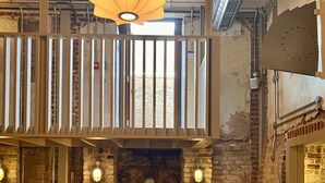 A cozy restaurant with a stone fireplace, wooden benches, and round tables.