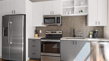 Una cocina moderna con electrodomésticos de acero inoxidable, armarios blancos y salpicadero de azulejos.