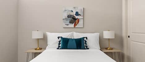 A hotel room with a large bed, two bedside tables with lamps, a wall-mounted artwork, and a door.
