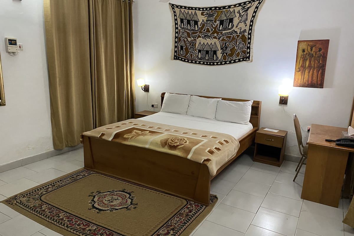 Una habitación de hotel con cama, mesitas de noche, escritorio y una silla.