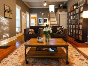 A living room with a wooden coffee table, two sofas, a bookshelf, and a staircase.