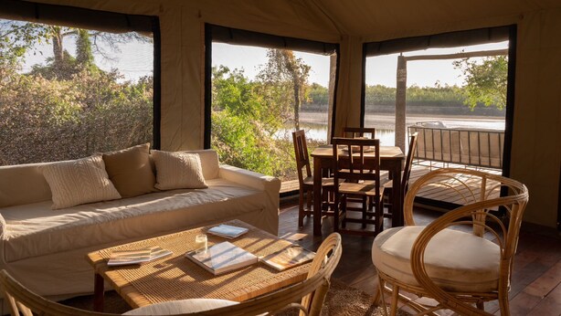 Una habitación acogedora con sofá, mesa y sillas, con vistas a un cuerpo de agua.