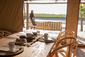 Un coin repas avec une table dressée pour deux personnes, donnant sur un plan d’eau.