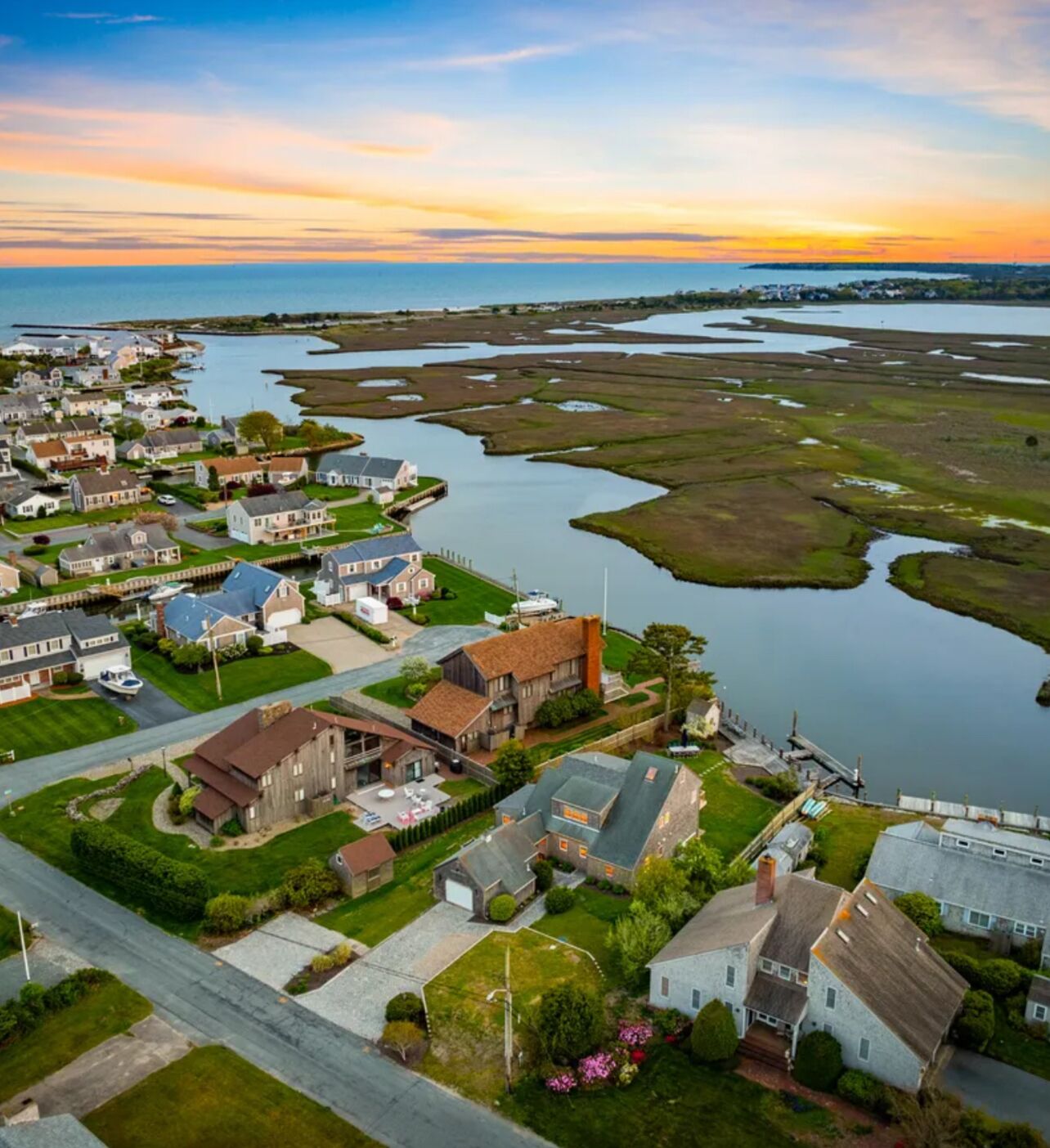 Luchtbeeld van een woongebied met huizen, een steiger en een groot waterlichaam.