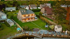 Una casa grande con un amplio patio trasero, un muelle y un cobertizo pequeño.