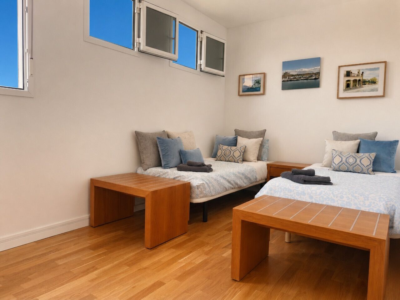 A bedroom with two beds, a wooden bench, and a bedside table.