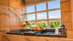 A bathroom with a marble wall, a window with a view of greenery, a sink with a fruit bowl, and a towel rack. - Villa Berria, 9 Pool / BBQ / Your Oasis near Palma (Es Pont d`Inca)