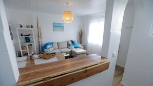 A modern living room with a wooden counter, a sofa, and a dining table. - Estrela do Atlântico (Açores)