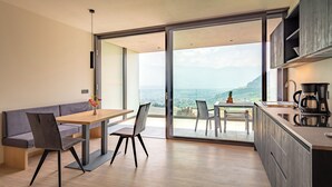 A modern kitchen with a large island, a dining area with a bench, and a view of the mountains through large sliding glass doors.