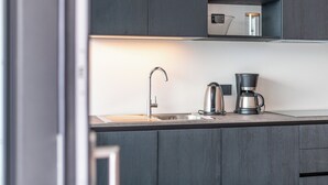 A modern kitchen with dark wood cabinets, a stainless steel sink, and a coffee maker.