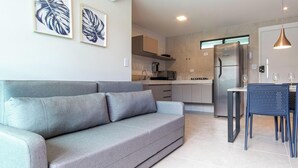 A modern kitchen with a refrigerator, stove, and microwave. There is a dining area with a table and chairs. - Porto Blue ao mar de Porto G - Carpediem (Ipojuca)