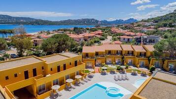 Un hotel con piscina, area salotto esterna e vista sul mare e sulle montagne.