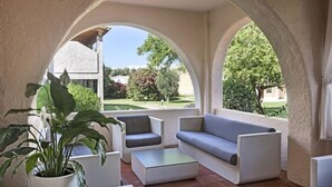 An outdoor seating area with a sofa, chairs, and a coffee table, framed by arches and potted plants. - Blu Hotel Laconia (Arzachena)