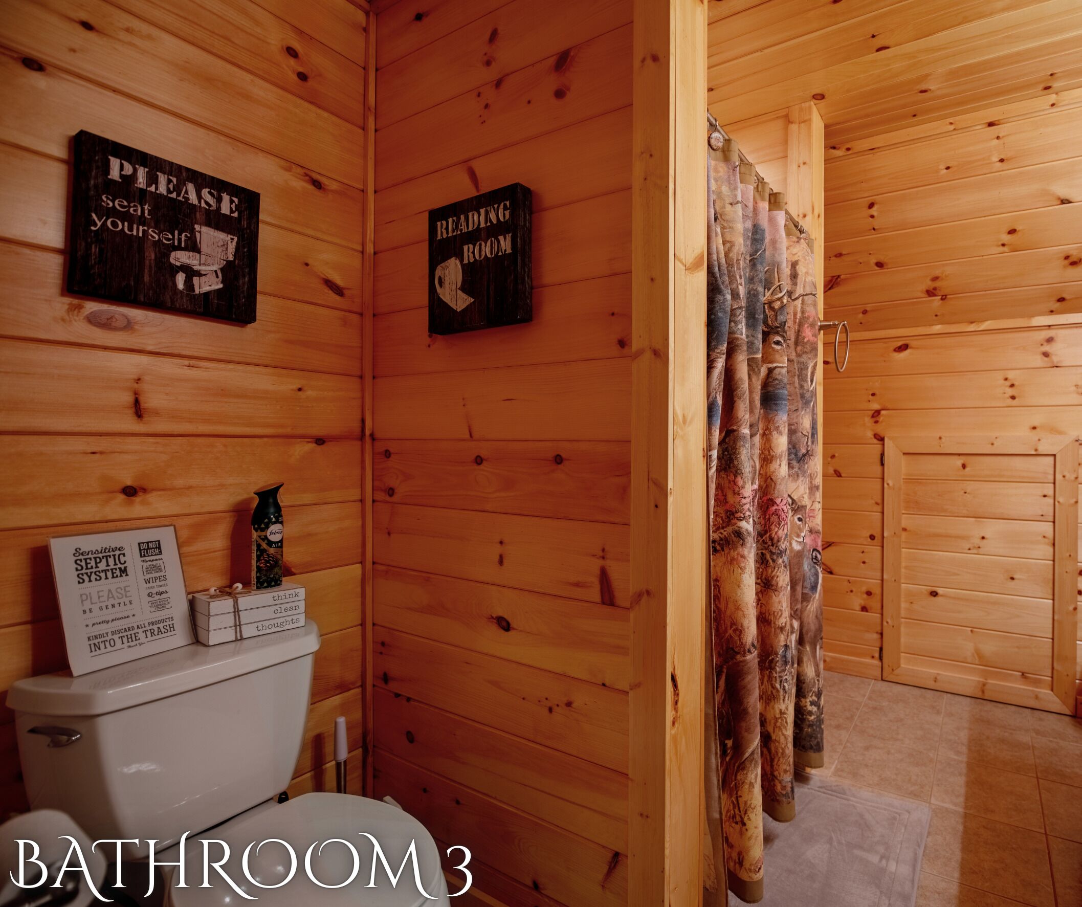 Une salle de bain en bois avec des toilettes, un panneau indiquant l’emplacement d’une salle de lecture et un autre panneau informant sur le système d’assainissement, qui nécessite une attention particulière.