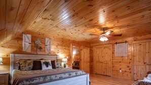 A wooden cabin bedroom with a bed, a ceiling fan, and a wall with a motivational quote. - *Timber & Tin* Family Retreat~Creek~Arcade~Hot Tub (Suches)