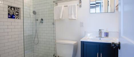 A bathroom with a shower, toilet, and sink.