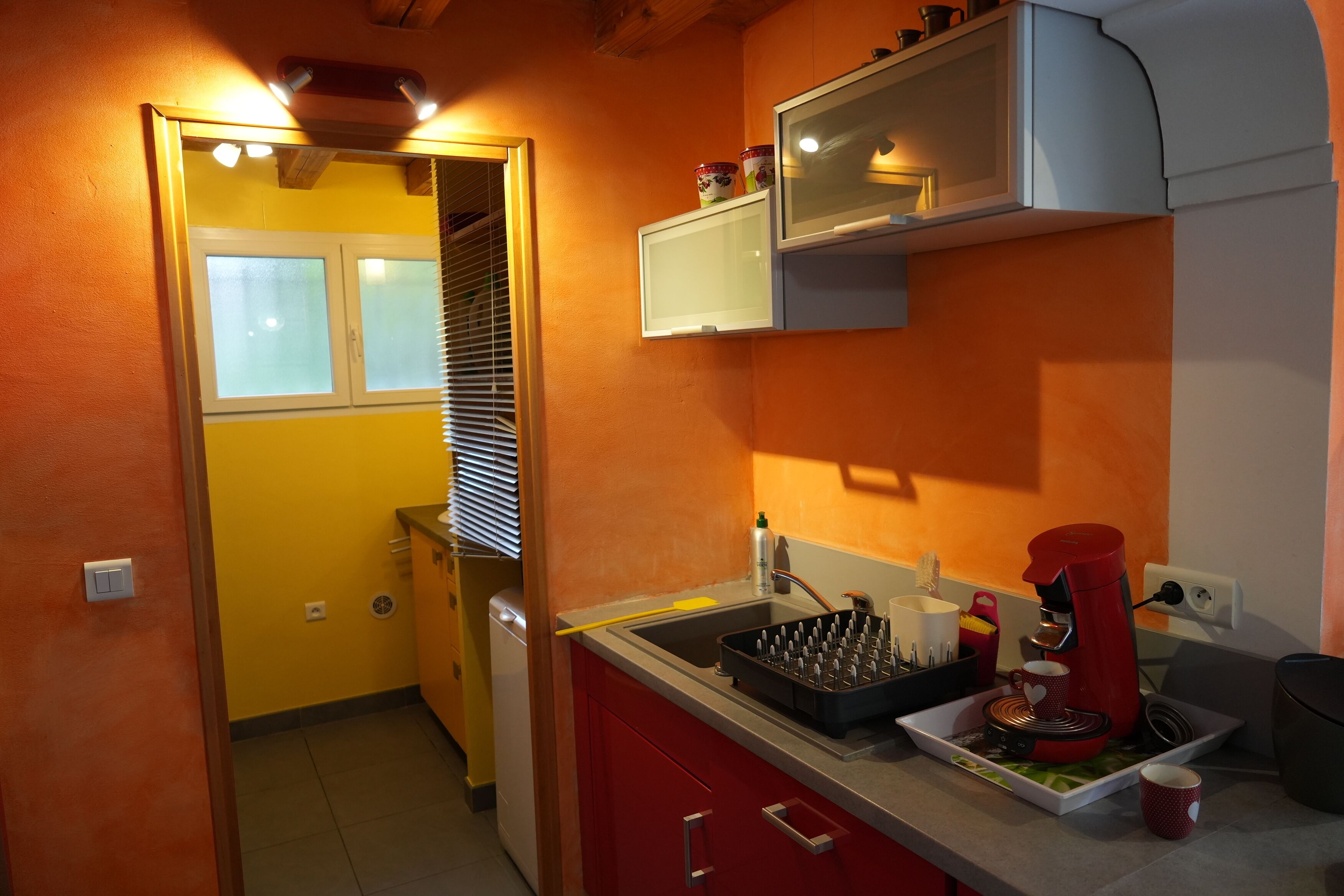 A compact kitchen with a built-in oven, a coffee machine, and a small sink.