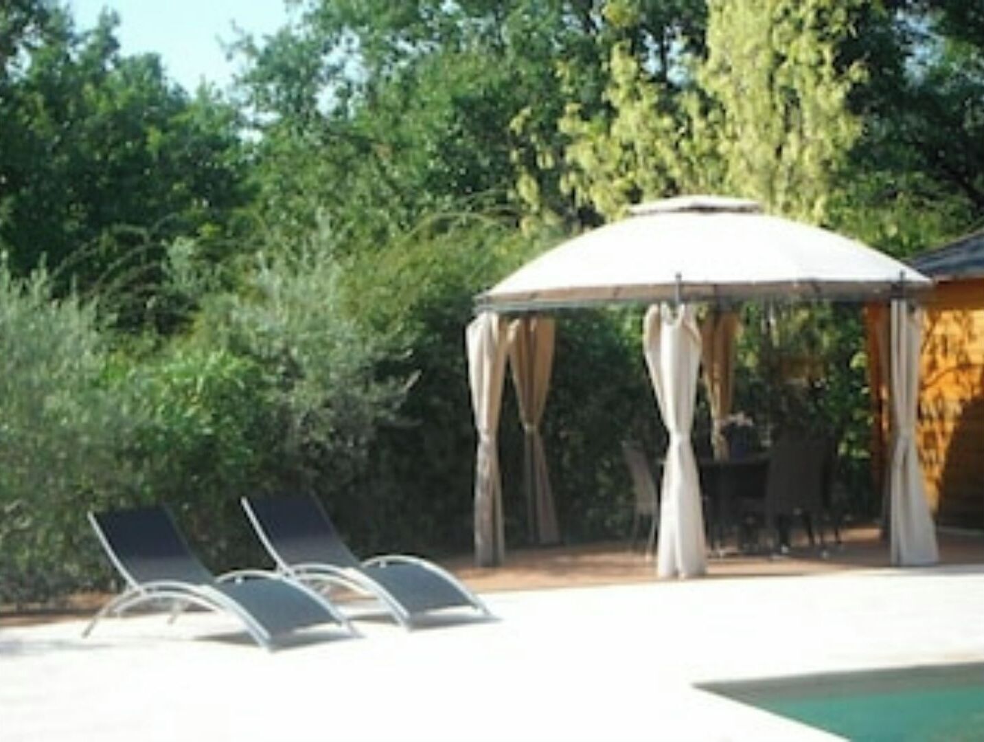 A gazebo with a white canopy and four lounge chairs.
