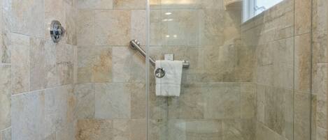 Ducha con puerta de vidrio, toallero y barra de apoyo.