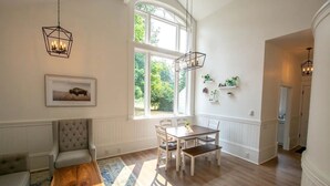 A dining area with a wooden table and chairs, a bench, and a large window with natural light.