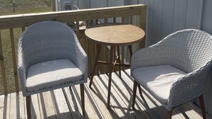 A deck with two wicker chairs and a small round table. - Centrally Located - Newly Built - Walk To The Beach! (Avon)