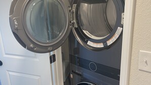 A laundry room with two front-loading washing machines and a dryer. - Centrally Located - Newly Built - Walk To The Beach! (Avon)