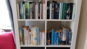 Une bibliothèque blanche, dotée de plusieurs étagères remplies de livres.