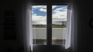 Une pièce avec vue sur la mer, donnant sur une fenêtre ornée de rideaux légers.