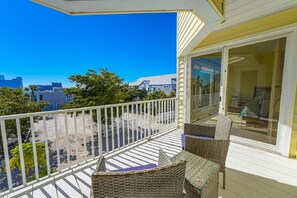 A balcony with wicker furniture and a glass door leading to an indoor area.