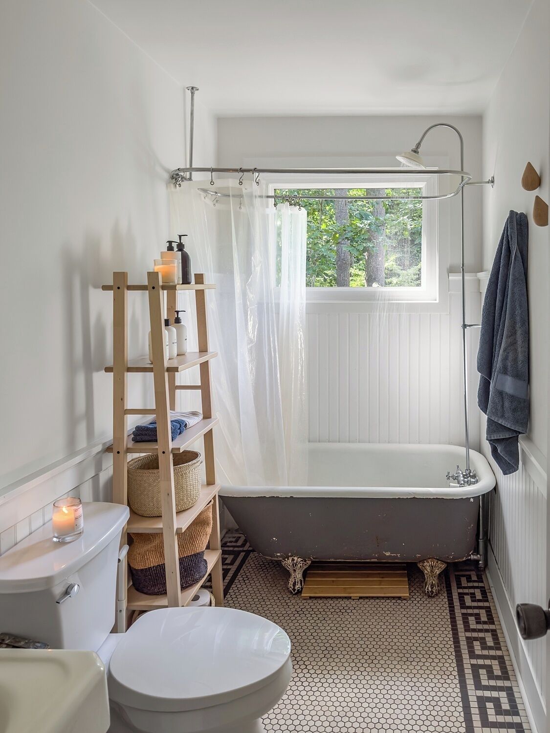 Een badkamer met een badkuip, toilet en een raam met uitzicht op groen.