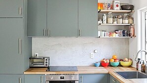 A modern kitchen with grey cabinets, a Bosch oven, a built-in toaster, and a wooden countertop.