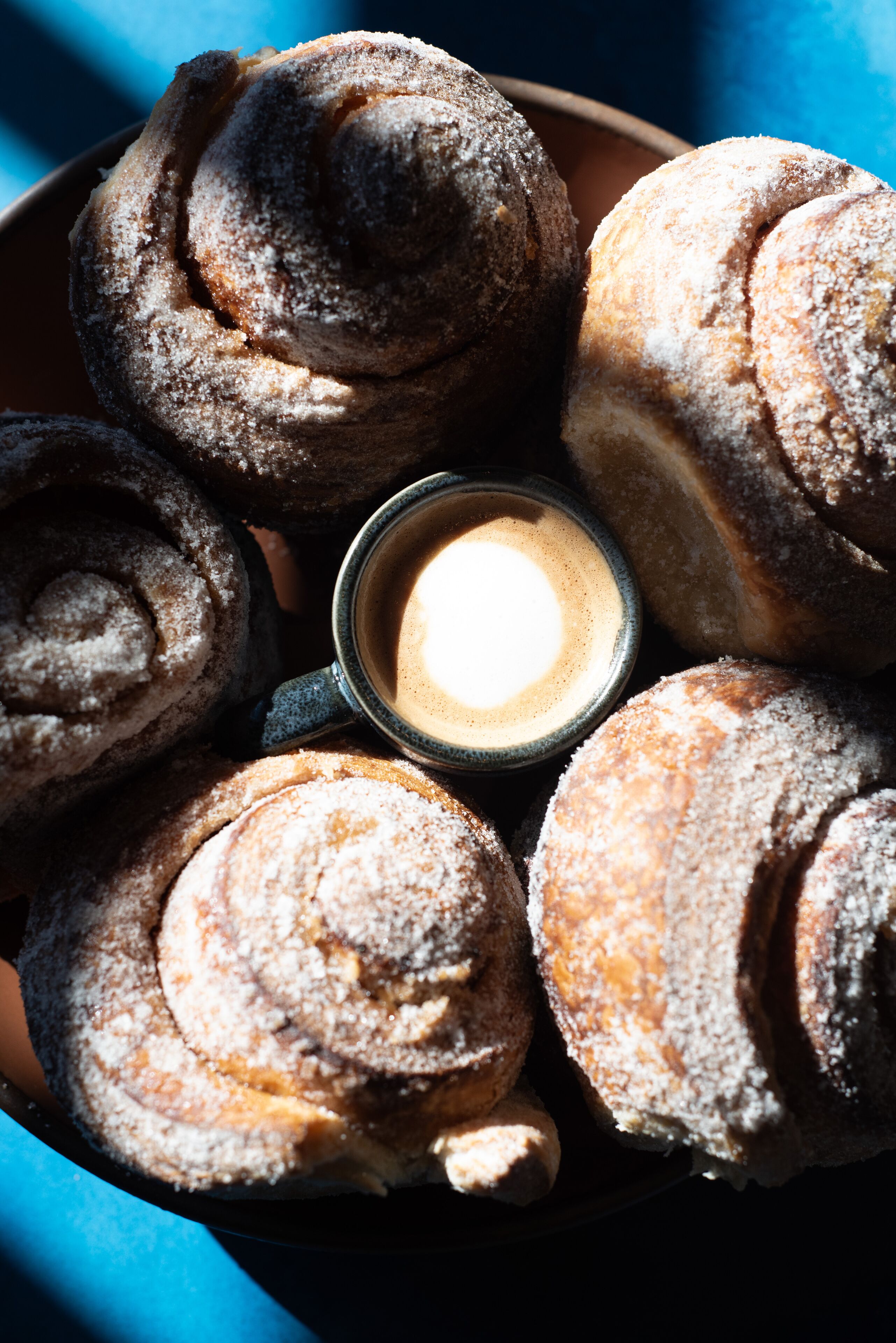 A tray of cinnamon rolls and a cup of coffee.